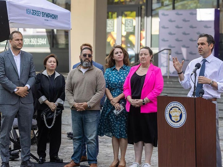 Mayor Steven Fulop speaking next to Jersey City legislative and comms members and Xian Zhang